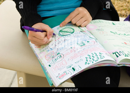 Student writing in notebook illustrated with doodles Stock Photo