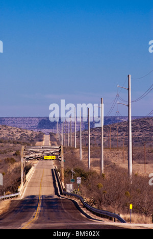 New power line and Pecos River bridge on Highway US-290 at sunset in Pecos River Valley, near Sheffield, Texas, USA Stock Photo