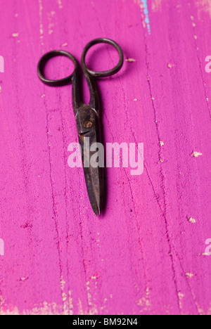 Old rusty pair of scissors over a pink wooden surface Stock Photo