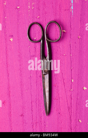 Old rusty barber's pair of scissors on a pink wooden background Stock Photo