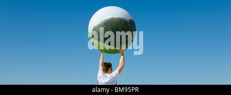 Holding aloft globe displaying image of forest Stock Photo