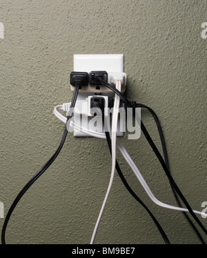 Multiple electrical plugs in overloaded wall outlet Stock Photo