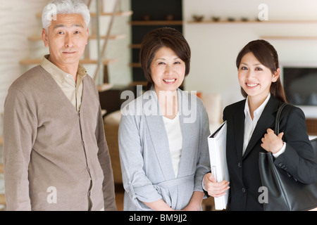 Portrait of young businesswoman and senior couple in living room, smiling Stock Photo