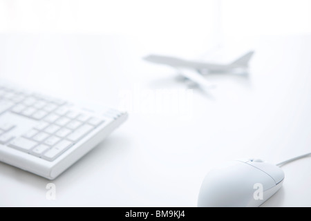 Computer keyboard, computer mouse and toy airplane on white background Stock Photo