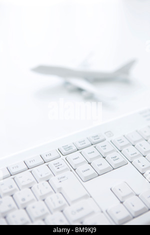 Computer keyboard and toy airplane on white background Stock Photo