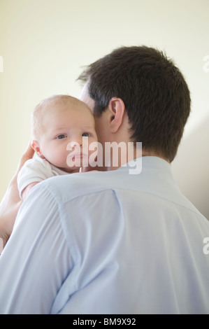 Father holds two week old newborn on his shoulder Stock Photo