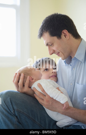 Father and son sit with two week old newborn baby Stock Photo