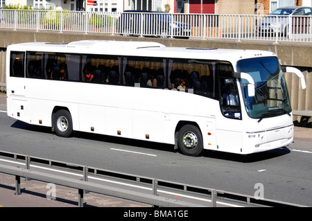 Unmarked clean white coach with obscured numberplate driving along A12 Brentwood bypass trunk road Essex England UK Stock Photo