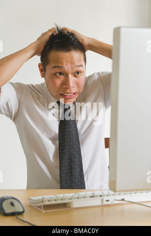 Businessman Pulling his Hair in front of Desktop Computer Stock Photo