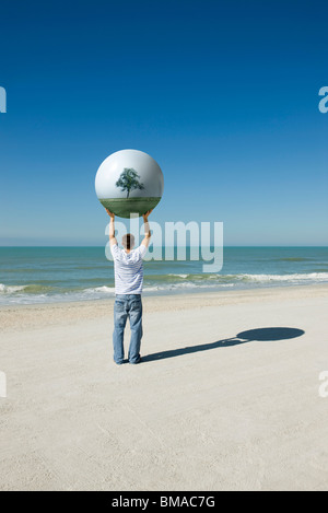 Holding aloft globe displaying image of trees Stock Photo