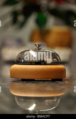 Detail shot of a service bell located on a hotel reception desk with blurred details in the background and reflection on marble Stock Photo