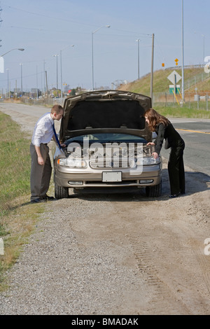 Man and Woman With Car Trouble Looking Under the Hood Stock Photo