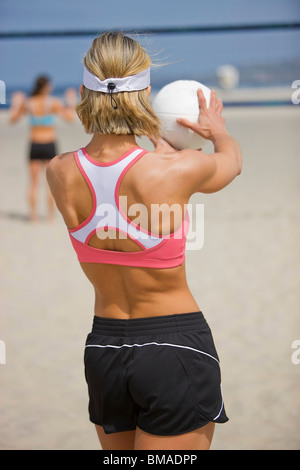 Female beach volleyball player serving volleyball, back view Stock Photo -  Alamy