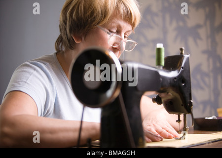Mature woman works at sewing machine Stock Photo