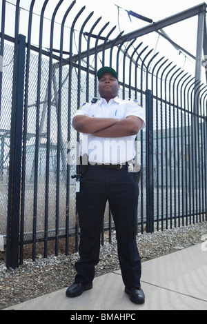 Security guard stands at strengthened prison fence Stock Photo