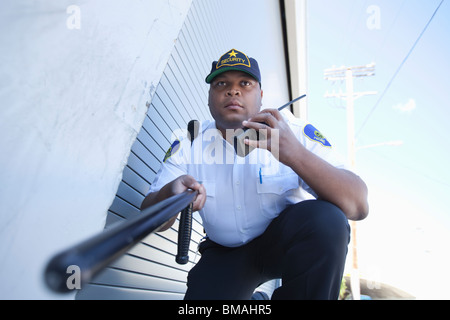 Armed security guard investigates with walk talky Stock Photo