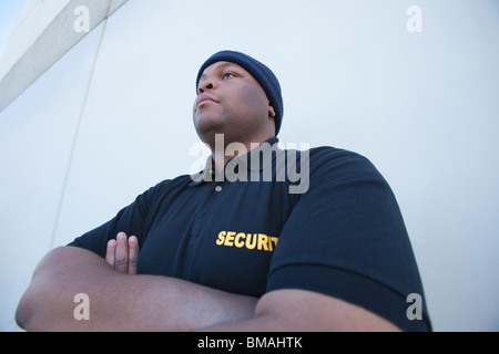 Security guard stands with arms folded Stock Photo