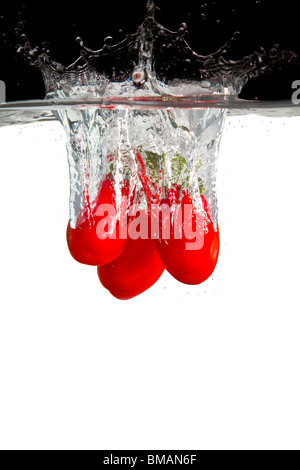 three red tomatoes thrown in water with black and white background Stock Photo