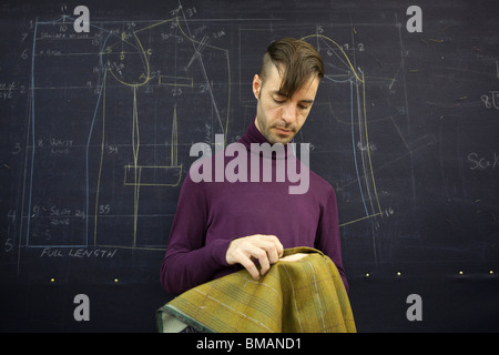 A tailor works inside the studio of Maurice Sedwell in Savile Row, London. Stock Photo