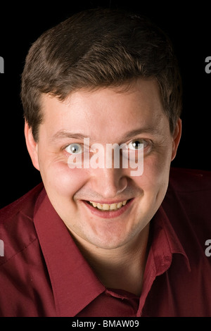 smiling green-eyed man in a red shirt on black background Stock Photo
