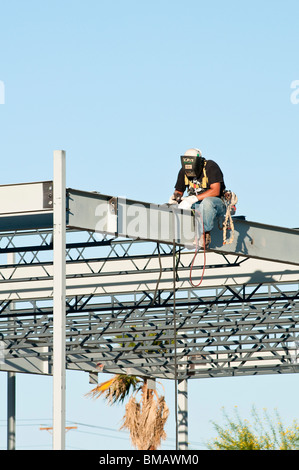 steelworker welds the structural steel framework for a commercial ...
