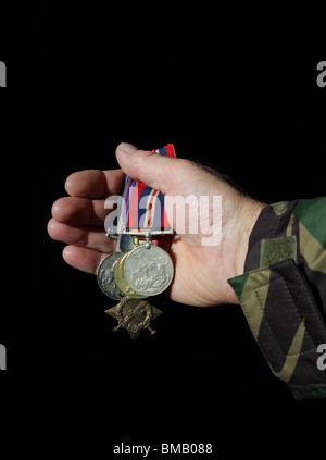 Collection of medals held in a soldiers outstreched hand. Stock Photo