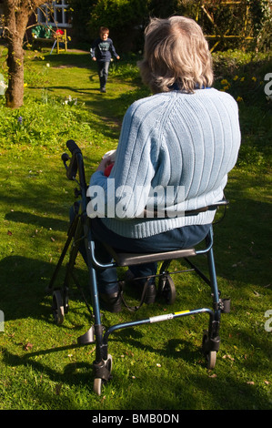 A MODEL RELEASED picture of an elderly woman with her rollator ( walking frame ) in a cottage garden in Suffolk , England , Uk Stock Photo