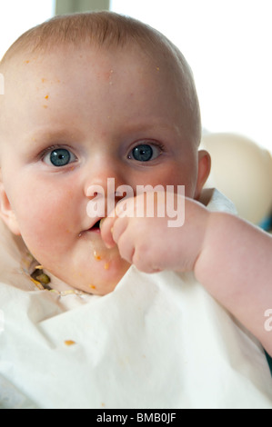 Baby putting food in his mouth Stock Photo