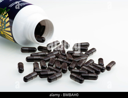 Acai Berry Capsules Spilling Out Of A Plastic Container, On To A White Background Stock Photo