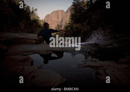 Hiker relaxing after a hard days waking next to a stream near refuge de Carruzzo on the GR20 in Corsica Stock Photo