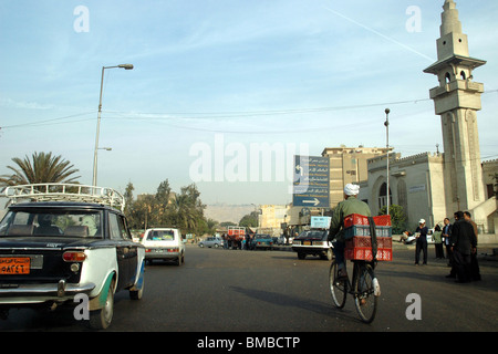 An Egyptian cyclist navigates car traffic and pedestrians on the road in the city of Cairo, Egypt.. Stock Photo