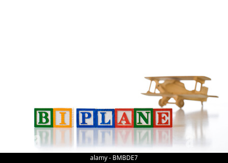 Colorful children's blocks spelling TOY PLANE with a toy wooden airplane Stock Photo