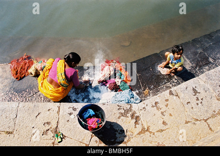 A woman and child washing clothes in Dhom Lake, in the town of Menavali, in the Western Ghats region of India. Stock Photo