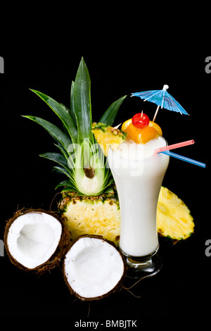 Pina Colada over black background, garnished with slice of pineapple and coconut. Stock Photo