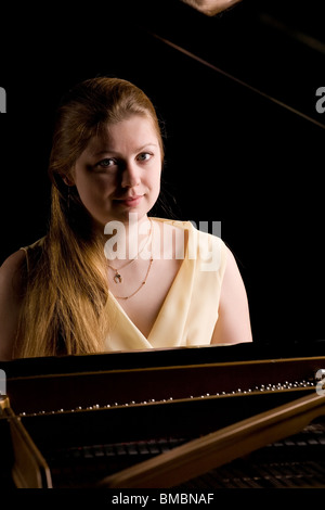 beautiful girl playing the grand piano, isolated on black Stock Photo