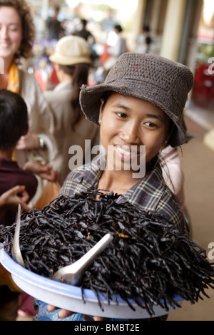 Woman carrying a plate of fried spider, Skuon village Cambodia. Known as Spiderville. Stock Photo