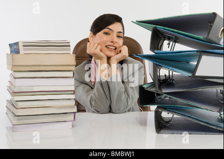 Stack of books and binders in front of a businesswoman at desk Stock Photo