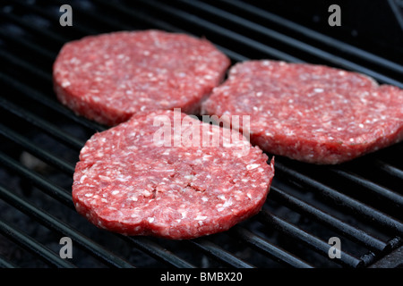 raw steak burgers cooking on a barbeque grill Stock Photo