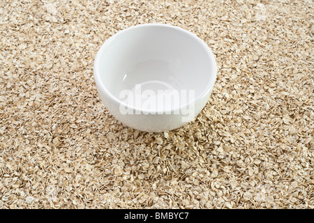 Empty white breakfast dish on a pile of porridge oats Stock Photo