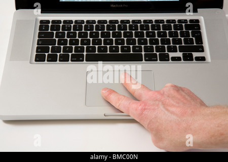 Fingers moving across an Apple Macbook Pro iBook Scrolling TrackPad / trackpad / track pad on an old vintage Apple laptop / lap top computer Stock Photo