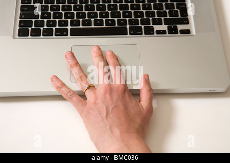 Fingers moving across an Apple Macbook Pro iBook Scrolling TrackPad / trackpad / track pad on an old vintage Apple laptop / lap top computer Stock Photo