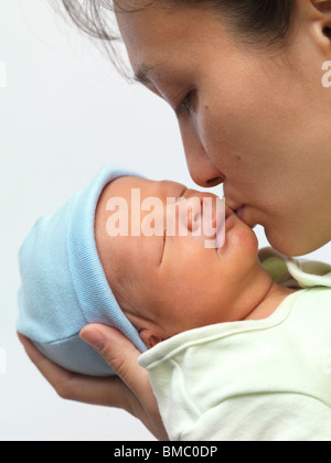 Mother kissing a sleeping newborn child baby boy on his cheek Stock Photo