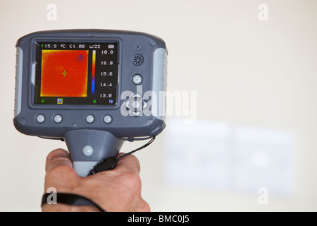 A technician uses a thermal imaging camera to check heat loss around light switchs in a house. Stock Photo