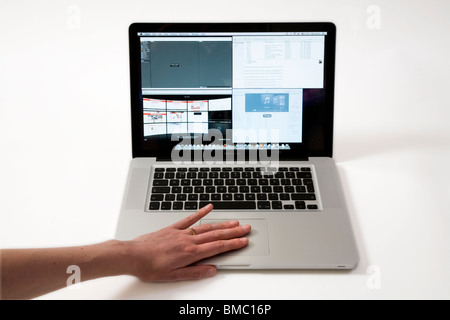 Hand & fingers moving across an old vintage Macbook Pro iBook Scrolling TrackPad / trackpad / track pad on an Apple laptop / lap top computer. Stock Photo