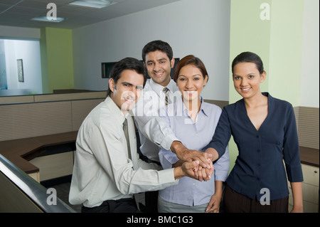 Business executives joining hands in an office Stock Photo