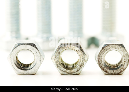 three silver bolts in front of screws on white background Stock Photo