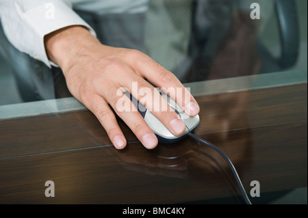 Close-up of a businessman's hand operating a computer mouse in an office Stock Photo