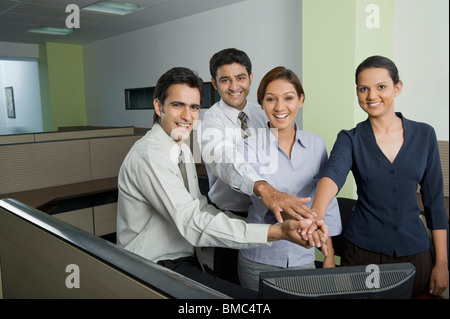 Business executives joining hands in an office Stock Photo