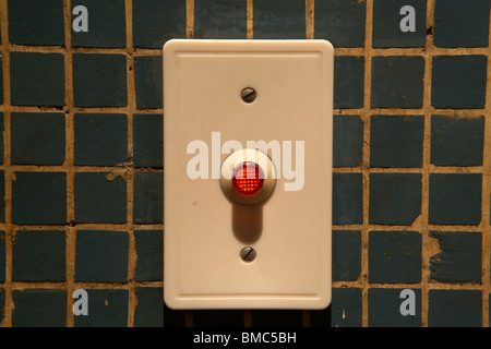 red light door buzzer button on a old tiled wall Stock Photo