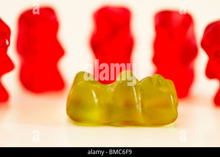 one green jellybear lies in front of red gummibears Stock Photo
